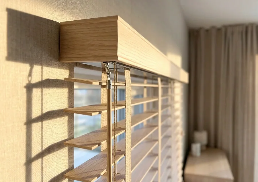 Timber venetian blind headrail, tilt mechanism and cords seen close up — the parts we service and repair